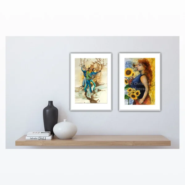 To kunstplakater hænger over hylde: den ene viser dansende par i blå nuancer, den anden en kvinde med solsikker.